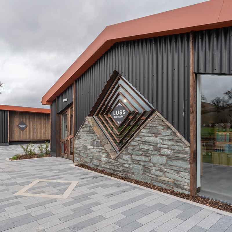 Modern building exterior with 'LUSS Distillery' logo on stone wall